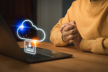 Man using laptop with futuristic concept of cloud computing download icon above laptop, symbolizing...