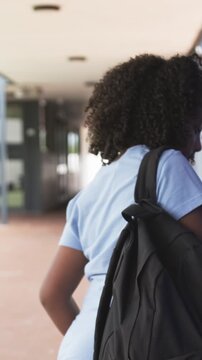 Vertical video: Noticing panel, African American child girl pressing it to enter walkway, walking