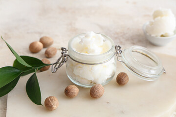 Glass with shea butter and nuts on table