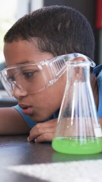 Vertical video: African American boy celebrating success after seeing liquid bubbling in lab flask