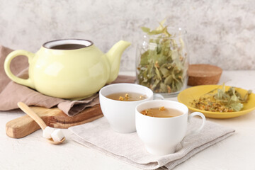 Cups of tasty linden tea with spoon, sugar cubes and napkin on white background