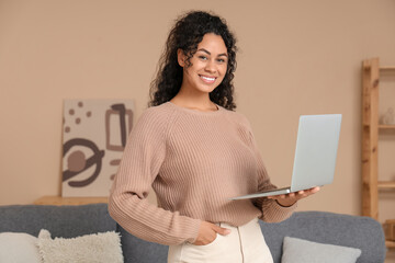 Pretty young African-American woman with laptop at home