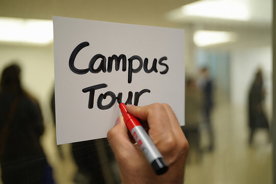 Hand writes campus tour on a note with a red marker inside a building