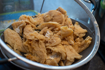 A metal dish containing cooked and cleaned salt cod fish. The dried and salted cod is white and flaky to preserve. The prepared food is for making cakes and brews with potatoes. The fillet is deboned.
