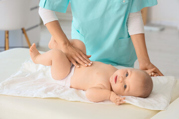 Female therapist massaging little baby's belly in clinic