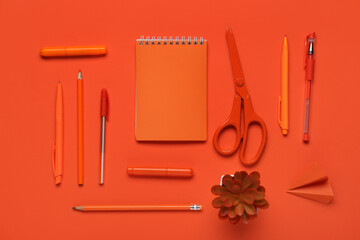 Different stationery supplies with paper plane and succulent on orange background
