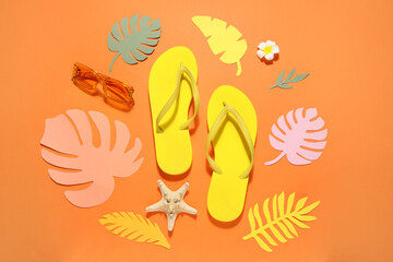Composition with stylish beach shoes, sunglasses and paper leaves on orange background, closeup