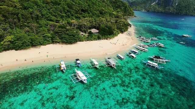 Scenic drone view of beach with boats and jungle in El Nido, Palawan island, Philippines Anchored boats and tourists on tropical beach in El Nido, Palawan, Philippines, aerial view