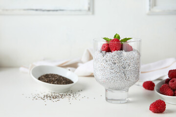 Glass of tasty chia seed pudding with fresh raspberries and mint on white background