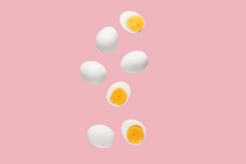 Flying many boiled chicken eggs on pink background