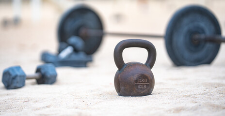Sport kettlebell training. Sport dumbbells on sand. Sporty outdoor fitness. Sport weightlifting...