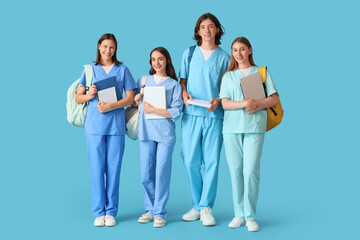 Group of medical students with backpacks and laptops on blue background