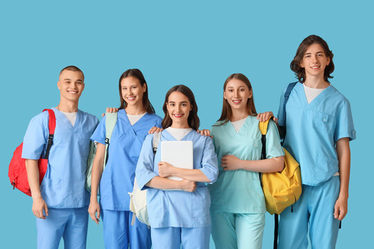 Group of medical students with backpacks and laptop on blue background - Powered by Adobe