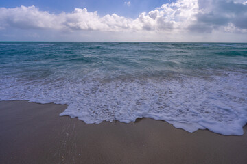Turquoise sea water wave motion. Summer beach. Calm sea. Luxury seaside resort. Bright sky and waves on beach. Beautiful foamy shoreline. Sea background. Blue ocean. Sandy beach. Sea waves.