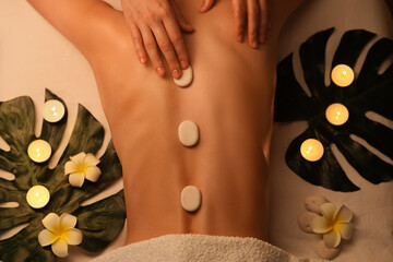 Woman getting back massage with stones in dark spa salon, top view