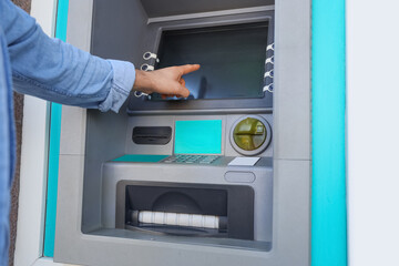 Young man withdrawing money from ATM outdoors