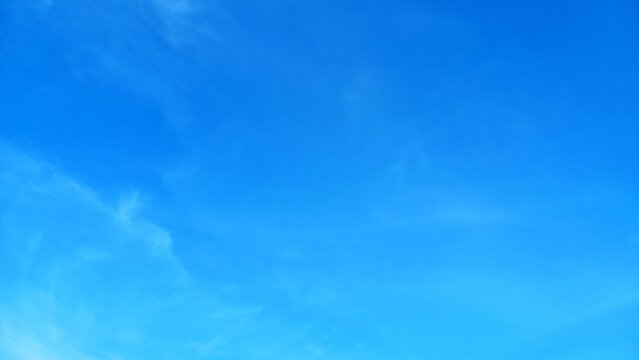 Clear blue sky with wispy white clouds on a sunny day.