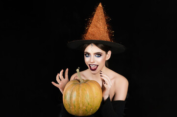Halloween woman portrait in witch hat with pumpkin. Halloween witch woman portrait in studio....