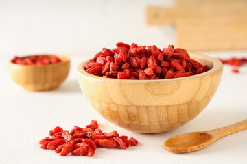 Wooden bowls with red dried goji berries on white background