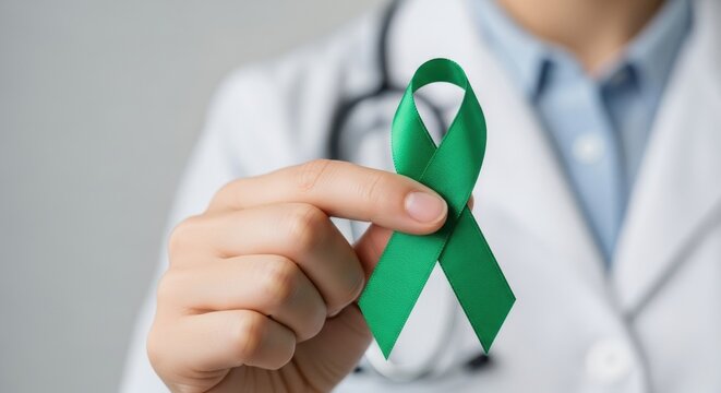 Doctor holding a green ribbon in hand wearing white coat and stethoscope around the neck in a clinic