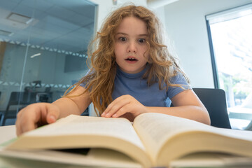 Surprised child reading book. Schoolkid studying and reading. Smart kid read book. Little student learning from book. Child reading book in library. Education and Learning. Knowledge through reading.