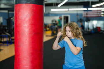 Kid boxing practice at gym. Boy hitting punching bag. Kid fighter. Sporty kid training hard. Strong sporty child. Youth workout in boxing ring. Active boy doing box exercise. Kid practicing martial.