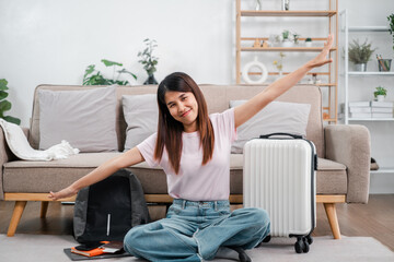 Smiling woman sitting on floor with suitcase and backpack, preparing for a travel adventure in a...