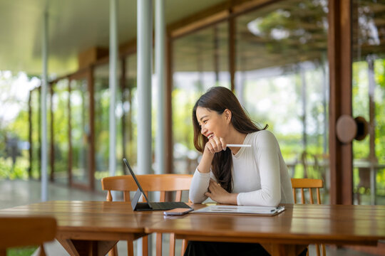 Happy freelancer woman working remotely on terrace using tablet and stylus