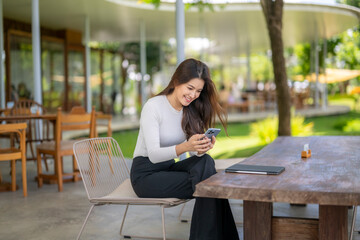 Smiling businesswoman using smartphone in outdoor cafe, enjoying break time
