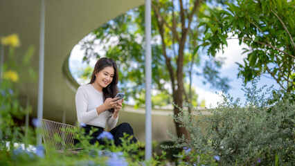 Young asian businesswoman using smartphone in green modern office space