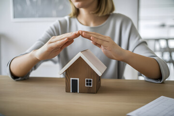 Home Protection Concept: A person carefully shields a miniature home, evoking a sense of security and protection, while subtly emphasizing the importance of safeguarding assets.