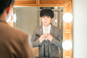 結婚式場のブライズルームで支度をするスーツ,タキシード姿の新郎
