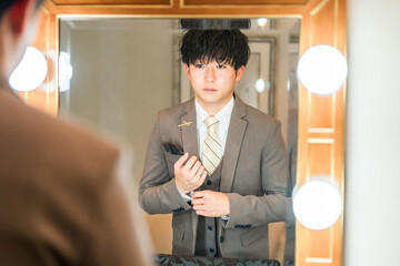 結婚式場のブライズルームで支度をするスーツ,タキシード姿の新郎
