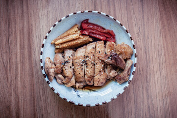 Grilled chicken with bell peppers and baby corn, topped with sauce and sprinkled with black and white sesame seeds.