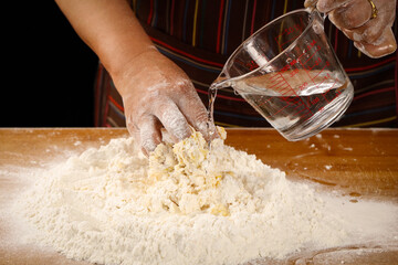 Making fresh bread dough by hand - kneading wheat flour with water in home kitchen