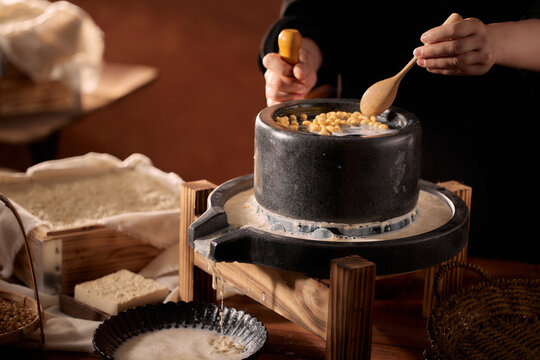 The Artisanal Process of Creating Tofu and Soy Milk by Hand,Grinding Soaked Soybeans with Stone Mill for Fresh Soy Milk