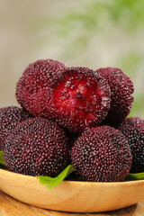 Fresh Red Bayberries in Wooden Bowl with One Cut Open Showing Interior Flesh
