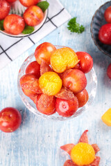 Fresh Red and Yellow Plums in Glass Bowl with Water Droplets on White Wooden Background