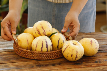 Fresh Yellow Pepino Melons in Wicker Basket on Rustic Wooden Table