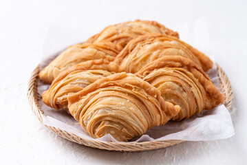 Curry puff stuffed with chicken or sweet potatoes in basket on white background, Thai snack food style