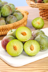 Freshly Harvested Green and Red Plums May Display Crisp Fruit on Wooden Kitchen Counter