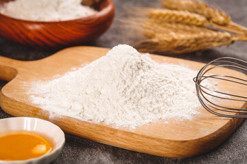 Fresh wheat flour on wooden board with baking ingredients for homemade bread making