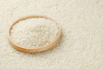 Fresh White Rice Grains in Wooden Bowl with Scattered Paddy on Surface