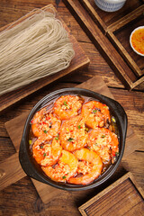 Garlic Shrimp with Noodles on Wooden Base - Traditional Asian Seafood Dish in Cast Iron Pan