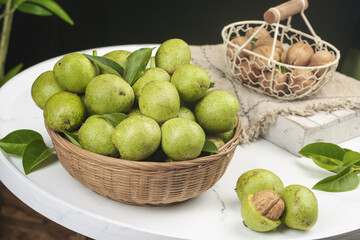 Fresh Green Walnuts in Wicker Basket with Pecans on Marble Surface - Natural Organic Harvest Display
