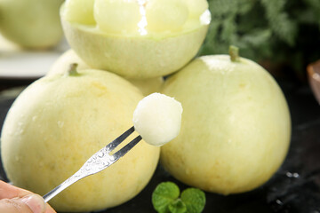 Fresh honeydew melon balls on spoon - healthy fruit dessert preparation