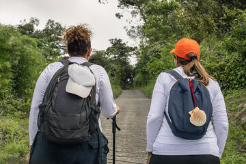 Two hikers walking along a paved trail on the Camino de Santiago