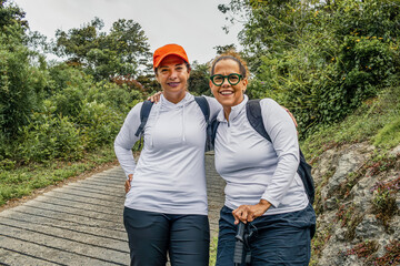 Portrait of smiling two female mature hikers resting on a scenic trail