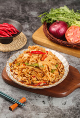 Asian Stir-Fried Rice Noodles with Vegetables and Chili on Wooden Board