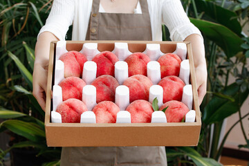 Freshly Picked Sweet Red Peaches in Wooden Gift Box Held by Woman in Apron